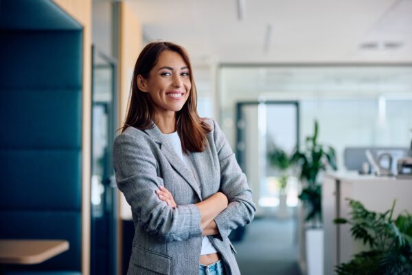 Young,Happy,Businesswoman,With,Arms,Crossed,Standing,Int,He,Office